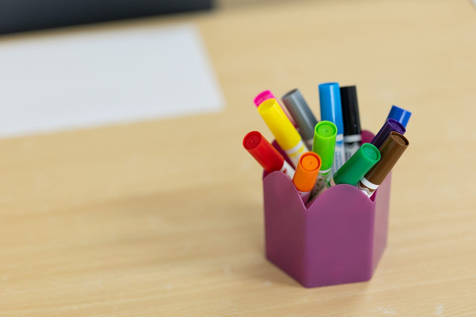 Pot of colourful markers on a timber table