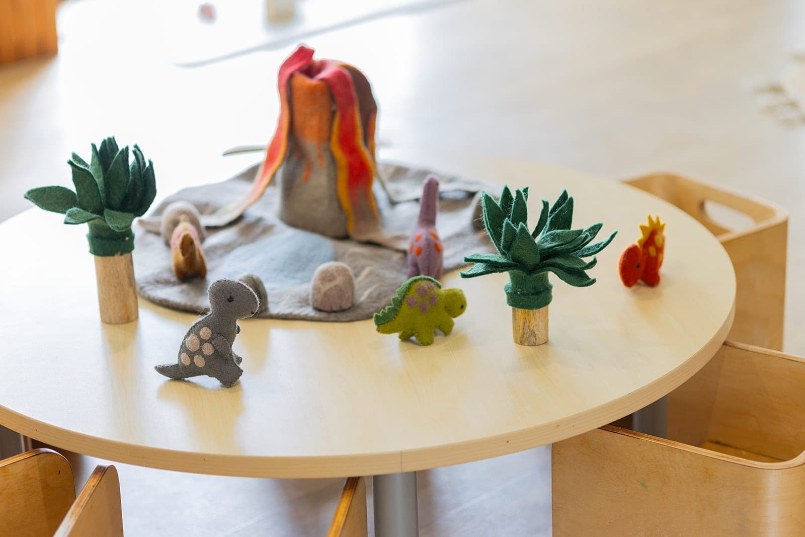 Small-world play table with a volcano, succulents and toy animals