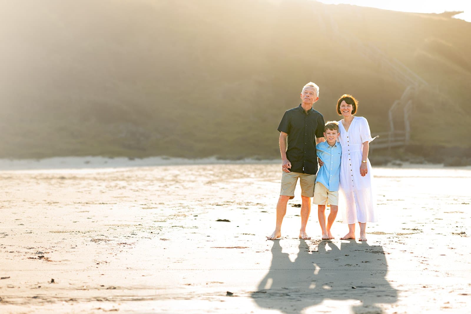 Family standing on the sand in warm afternoon light with long shadows
