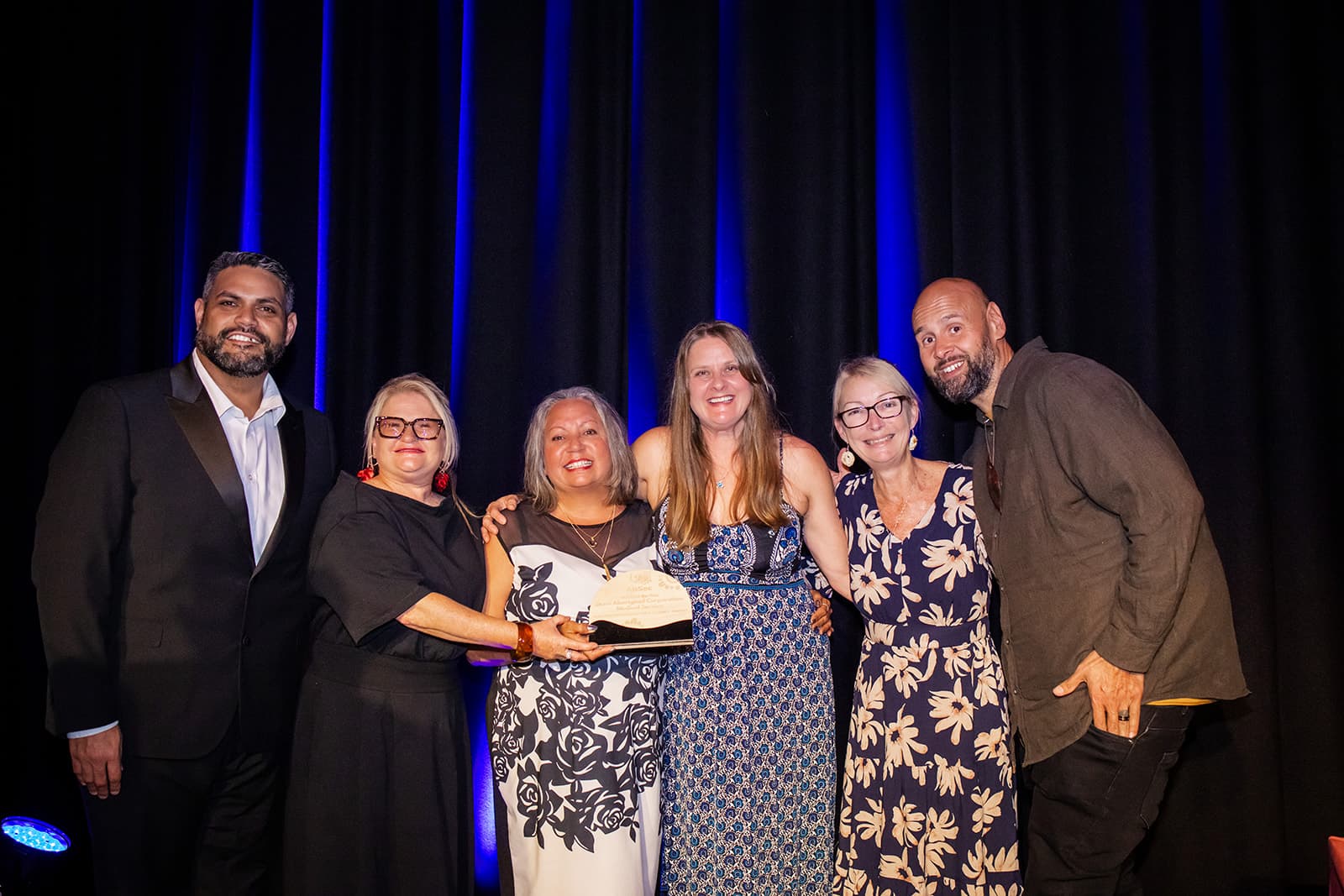 A team of award recipients on stage with presenters