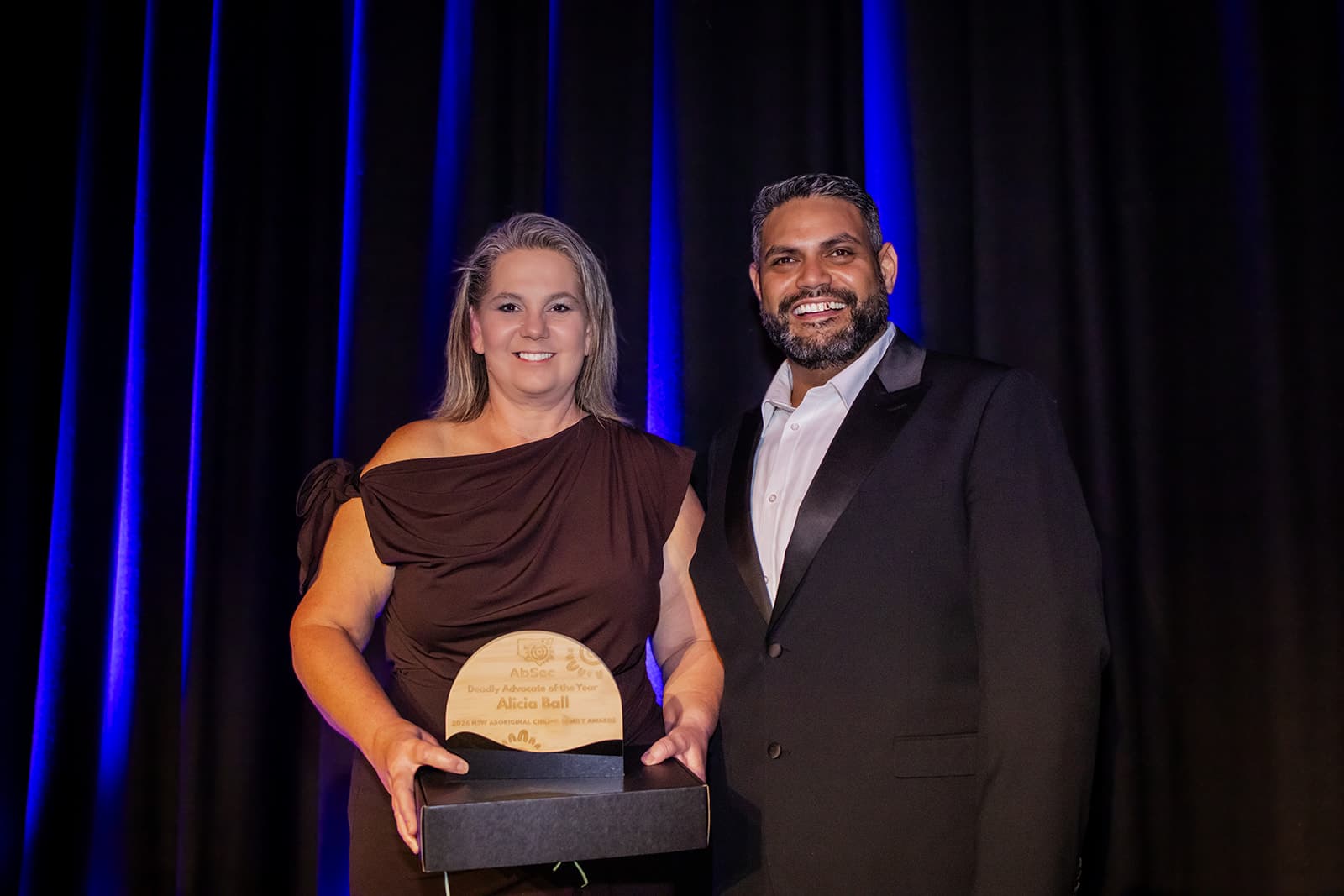 Two recipients and presenters with their award on stage