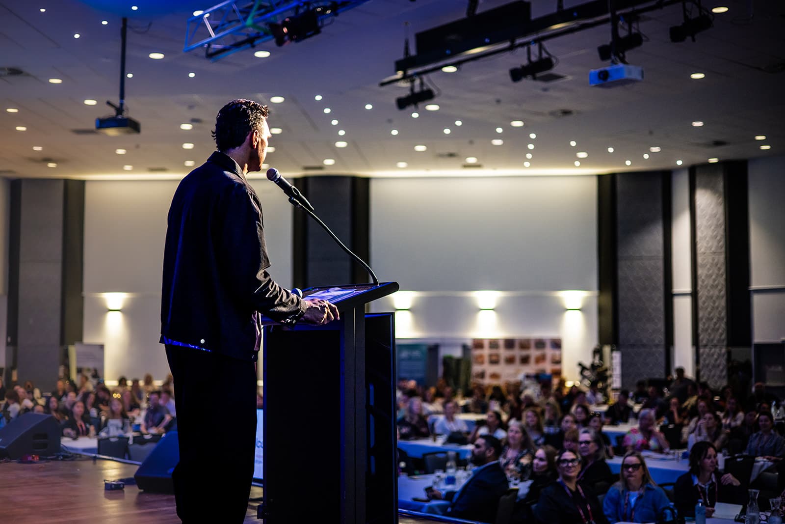 Keynote speaker at the lectern addressing a full AbSec conference room