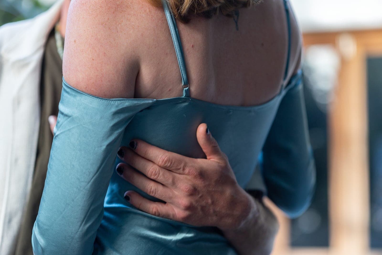 JoJo's hand resting on the back of Chloe's blue satin dress