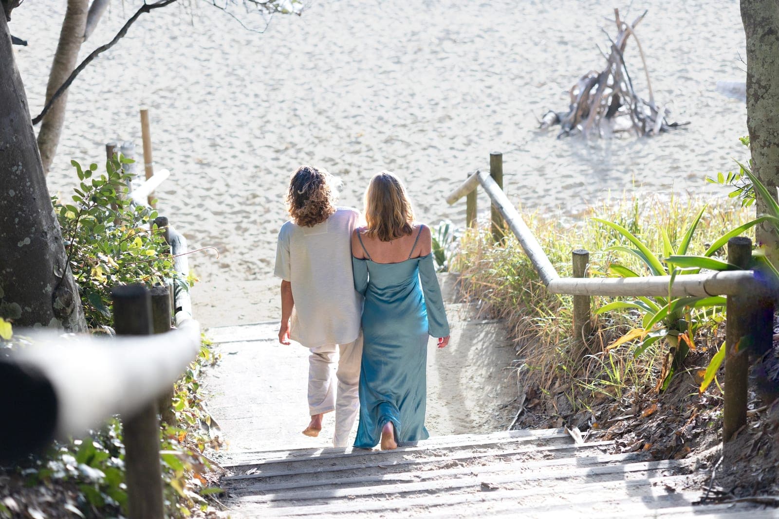 Chloe and JoJo walking arm in arm down the beach stairs toward the sand
