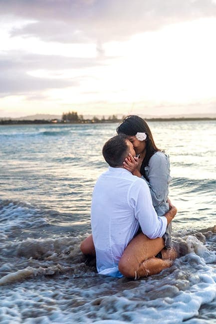 Couple kissing in the shallows at dusk with a flower in her hair