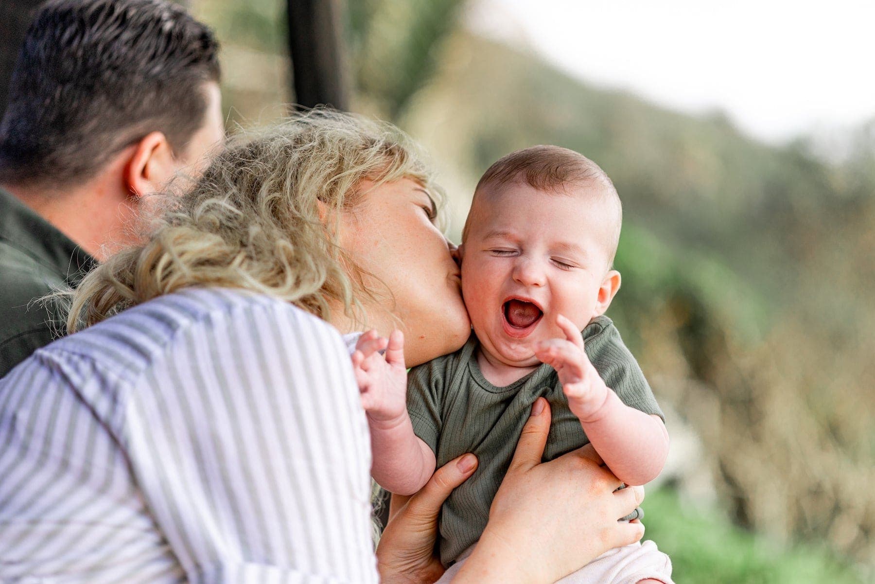 Mother kissing her laughing baby