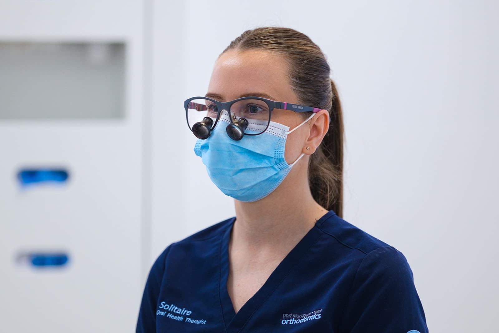 Oral health therapist wearing magnifying loupes and a mask