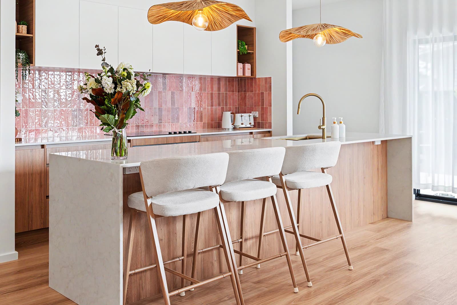 Kitchen with pink zellige splashback, timber cabinetry and bar stools