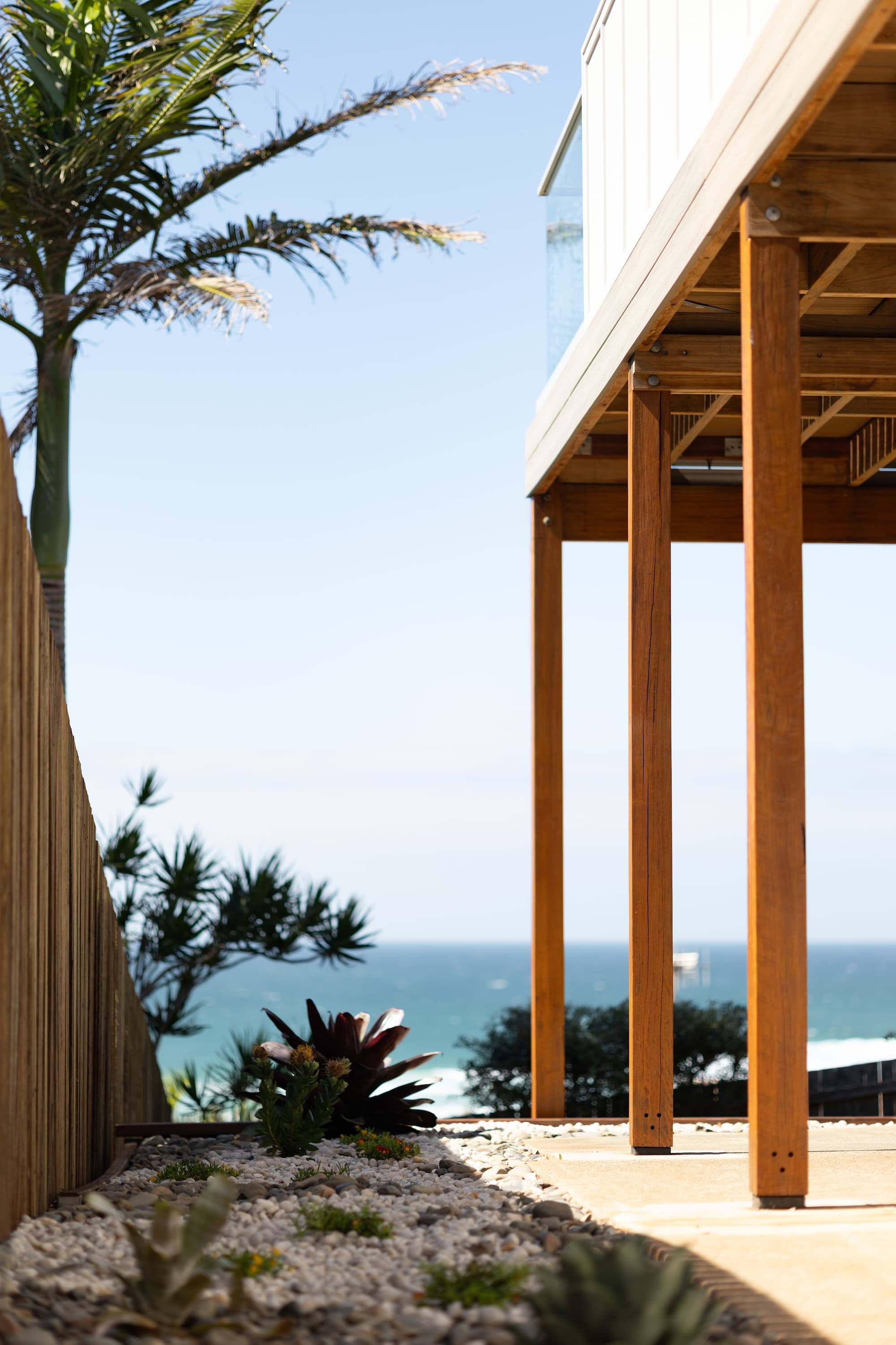 Hardwood posts under a deck framing a view of the ocean