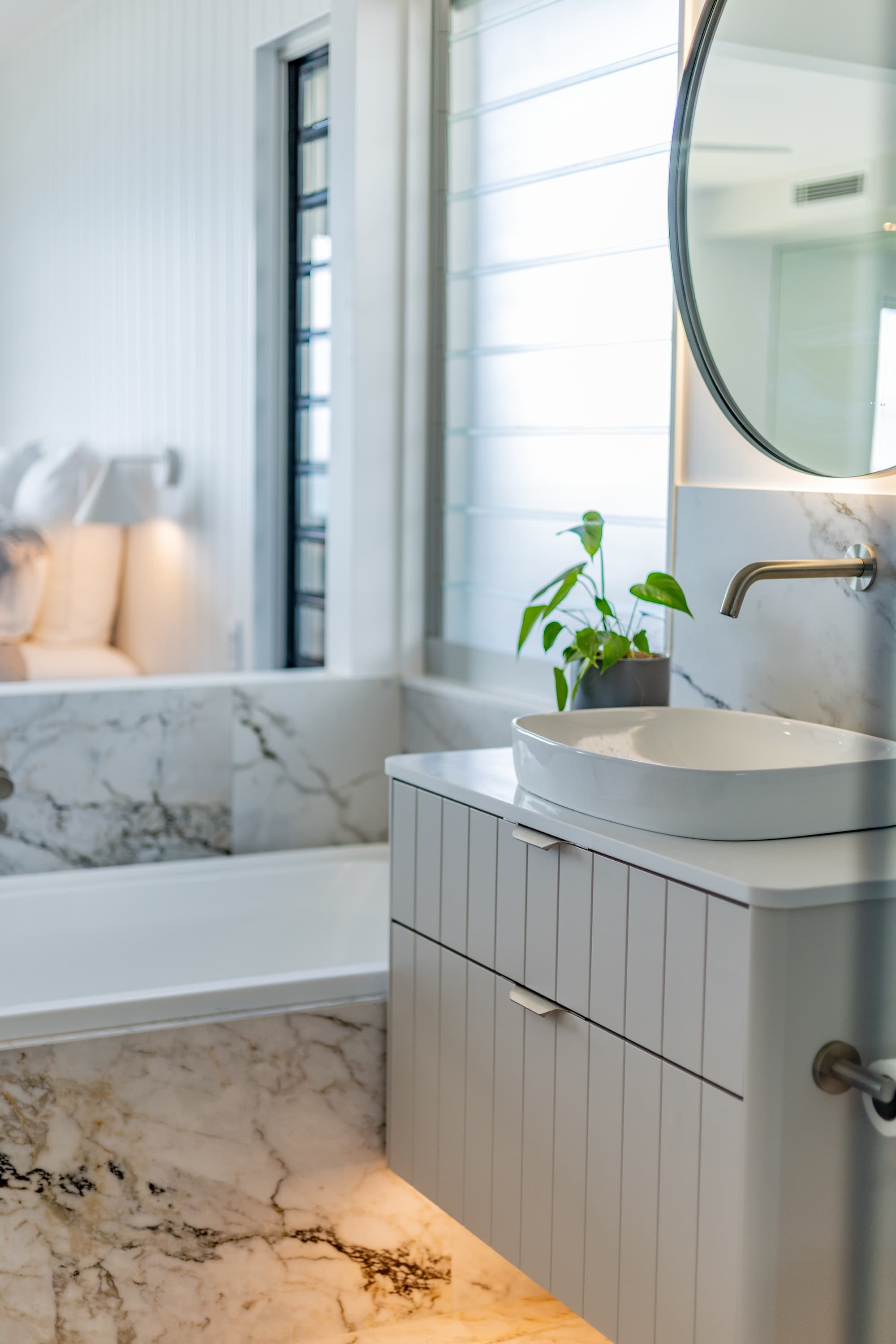Bathroom vanity with a round mirror, vessel basin and potted plant