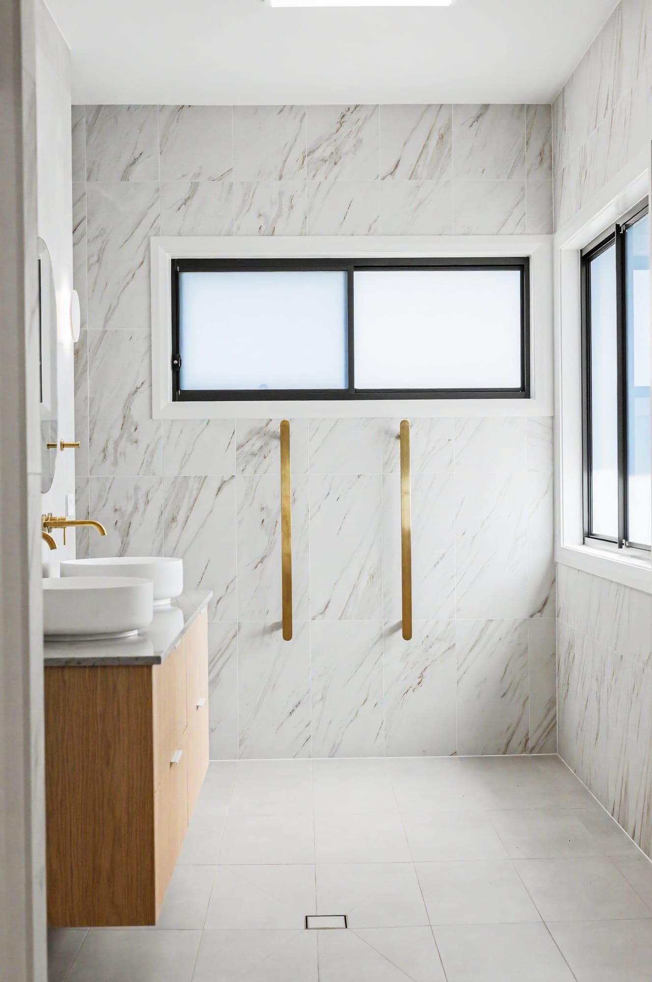 Marble-tiled ensuite with brass towel rails and a floating timber vanity