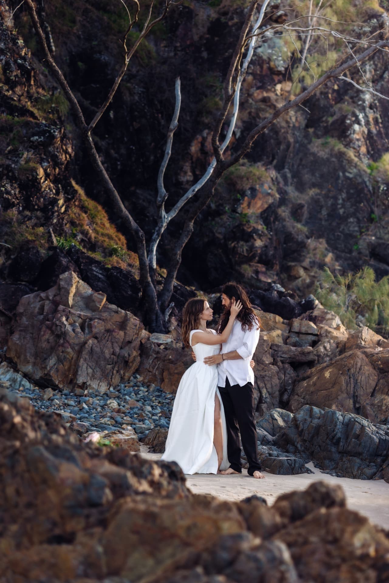 Couple embracing among coastal rocks and trees