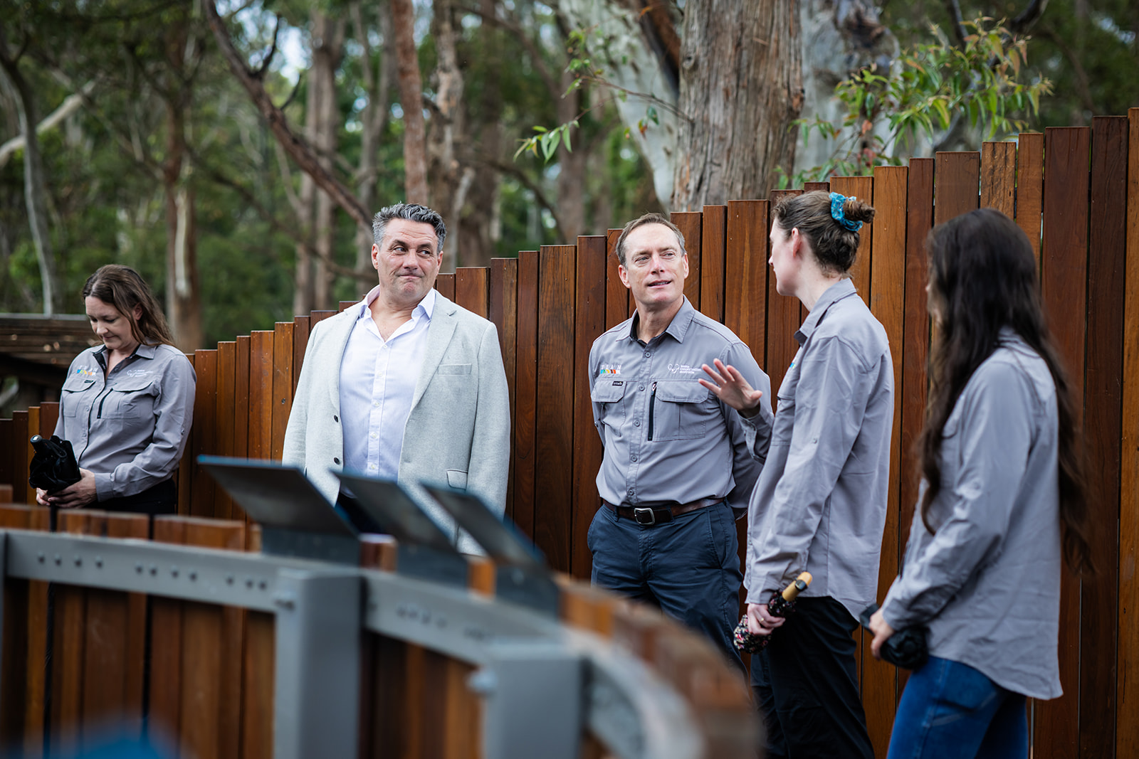 Koala Conservation Australia staff chatting with the sponsor representative beside the timber enclosure fence