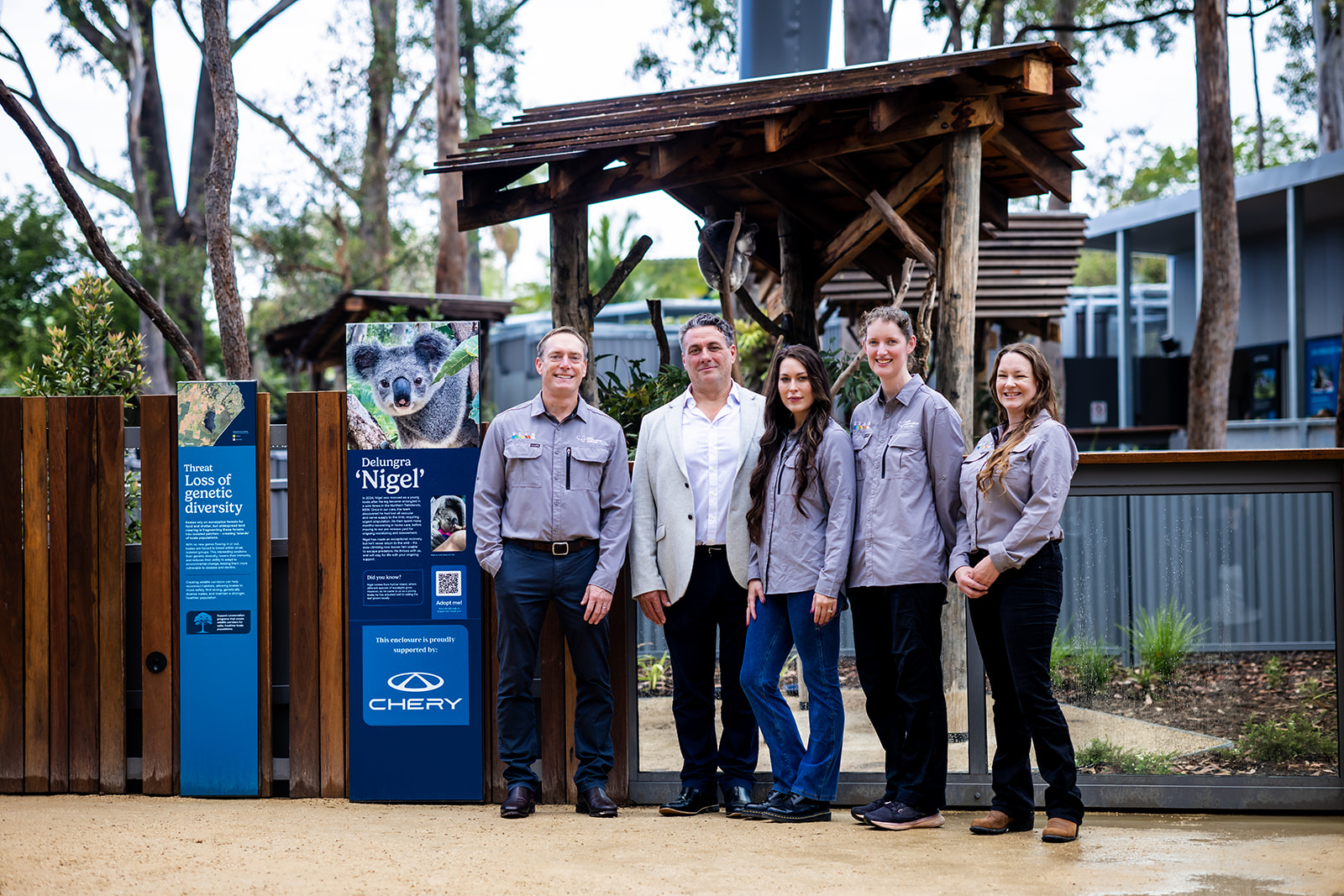 Group portrait of the sponsor representative and Koala Conservation Australia team in front of Nigel's enclosure and the sponsor sign