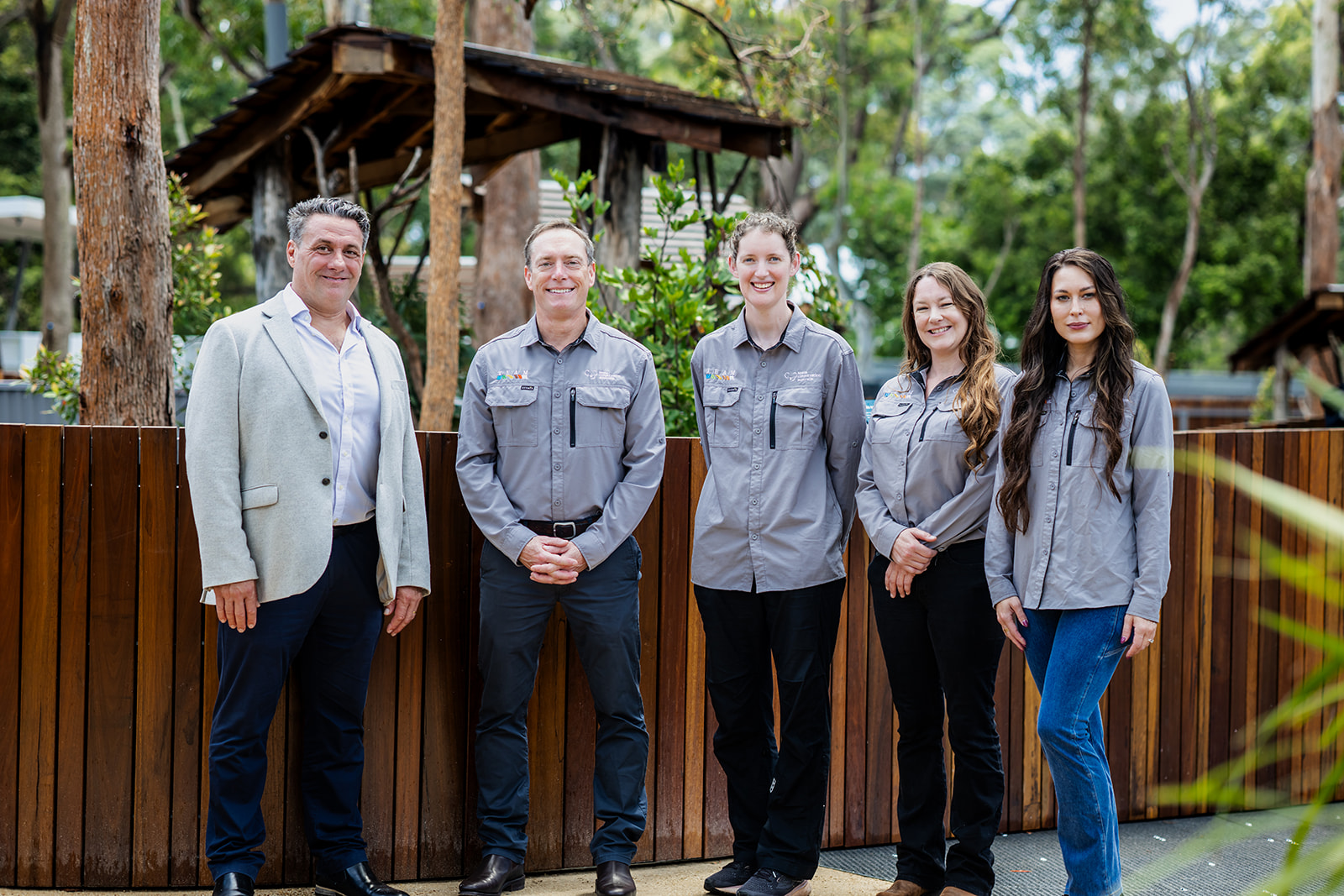 Automotive sponsor representative standing with four Koala Conservation Australia team members in front of a timber fence