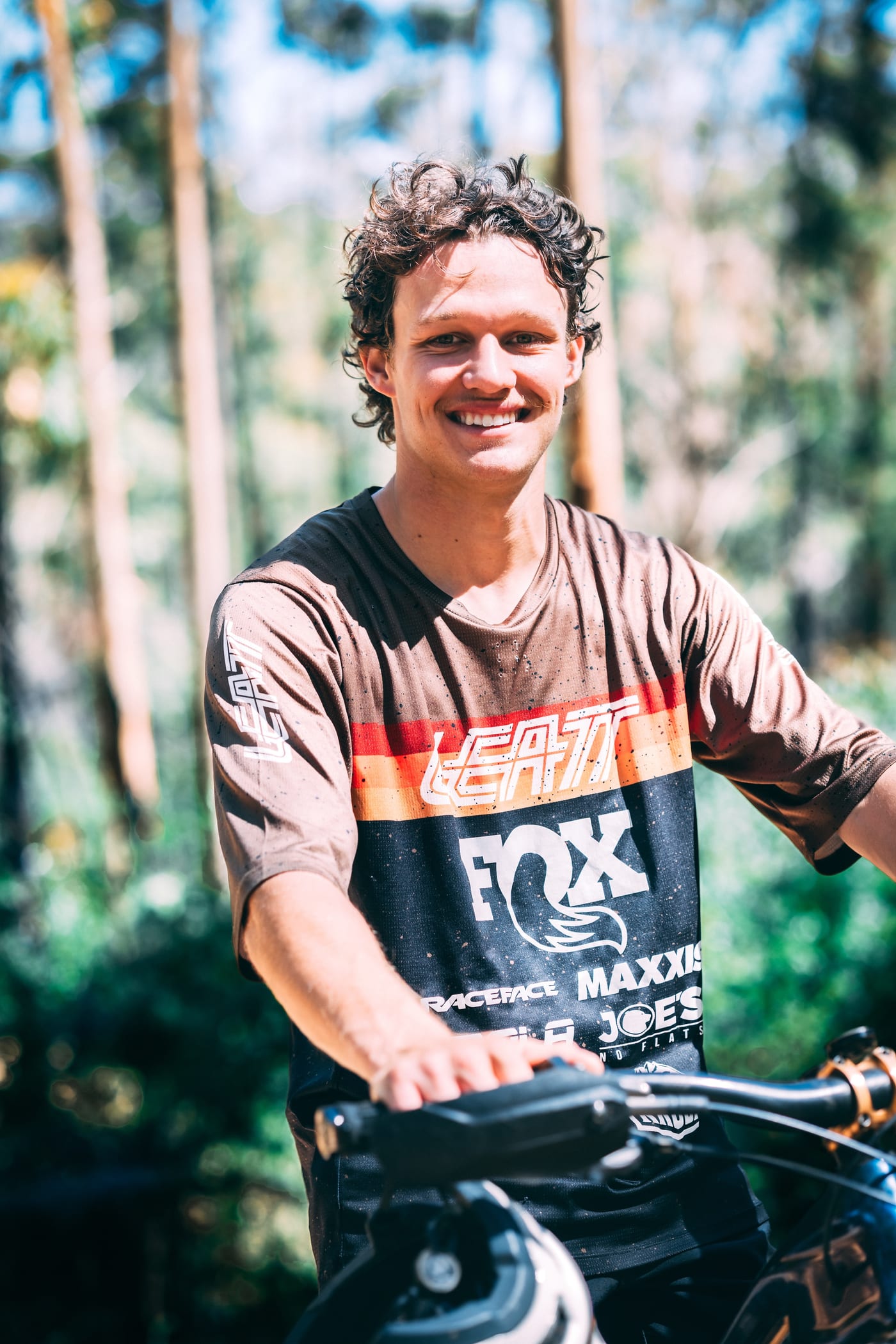 Tom Jenkins smiling on his mountain bike in the bush